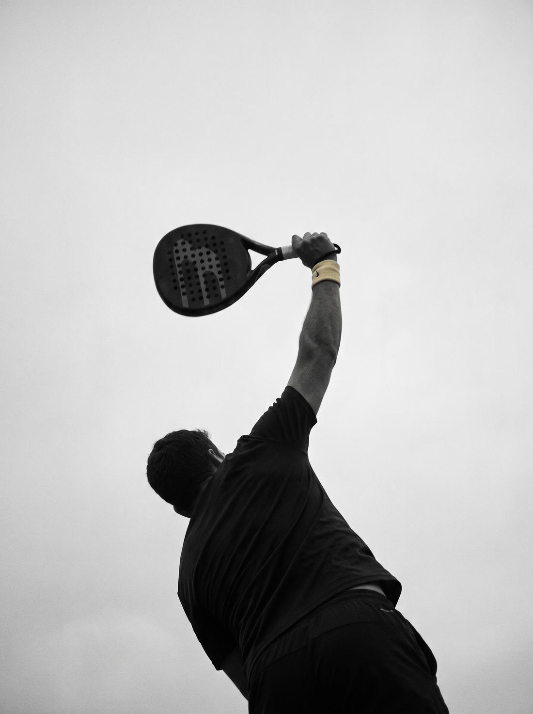 Siluet pemain padel mengangkat raket di puncak ayunan smash