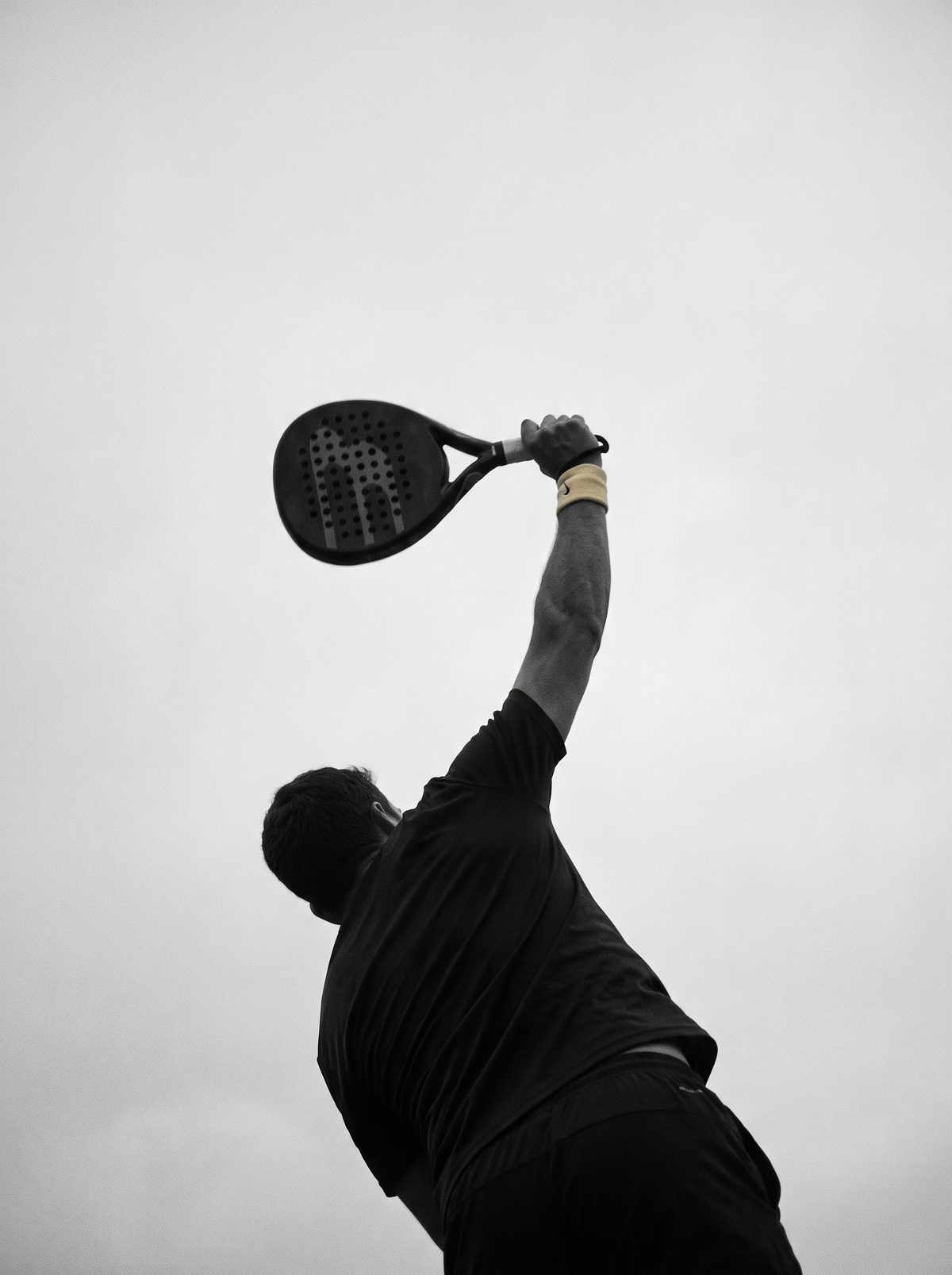 Siluet pemain padel mengangkat raket di puncak ayunan smash