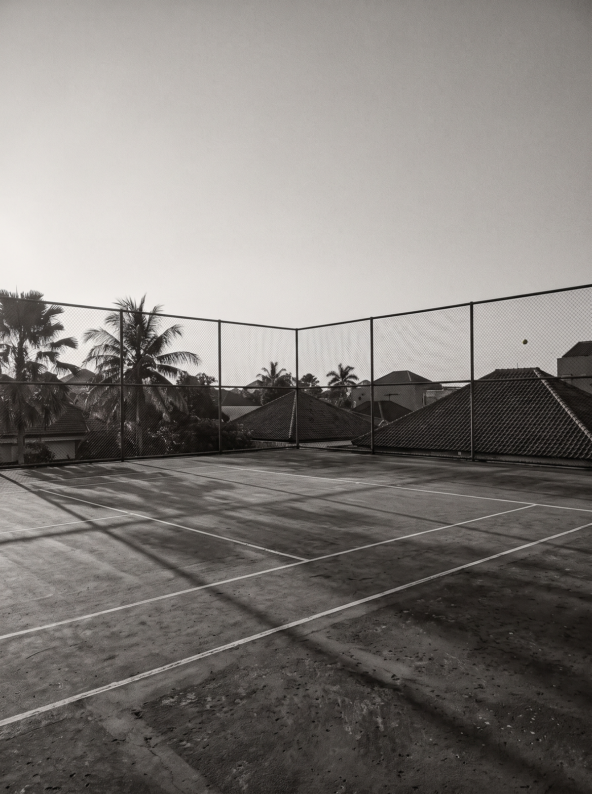 Lapangan tenis outdoor kosong di kota tropis pada sore hari